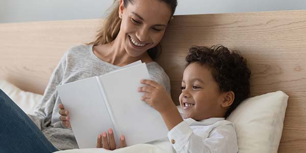 Hispanic mother and son reading in bed